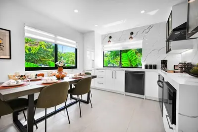 a white kitchen with a table and chairs in it at Stylish Modern Home near Wynwood & Design District in Miami