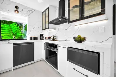 a white kitchen with black appliances and a window at Stylish Modern Home near Wynwood & Design District in Miami