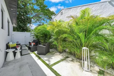 a courtyard with palm trees and a white fence at Stylish Modern Home near Wynwood & Design District in Miami