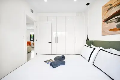 a white bedroom with a bed with a teddy bear on it at Stylish Modern Home near Wynwood & Design District in Miami