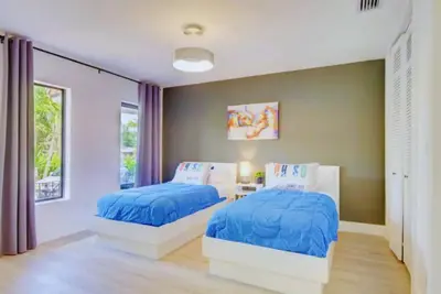 two beds in a bedroom with blue comforter at Club House 305 w PRIVATE NIGHTCLUB, Cinema, Game Room, Gym & Pool in Miami