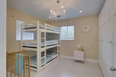 a bedroom with bunk beds in a room with a chandelier at The Palms Villa with Cinema, Game Table, Pool, Jacuzzi , Giant Chess, 8 Beds in Miami