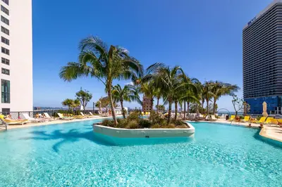 a large swimming pool with palm trees and chairs at Wonderful 1 Bed - Amazing views in Miami