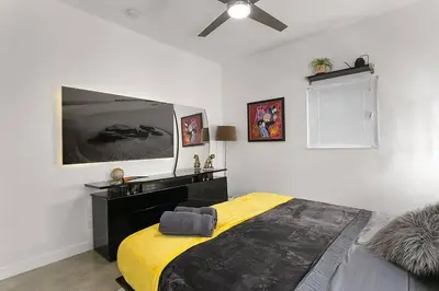 a bedroom with a bed and a tv on the wall at Luxury Mansion, Game Room, Pool, Rooftop, Skyline, Walk to Las Olas in Fort Lauderdale