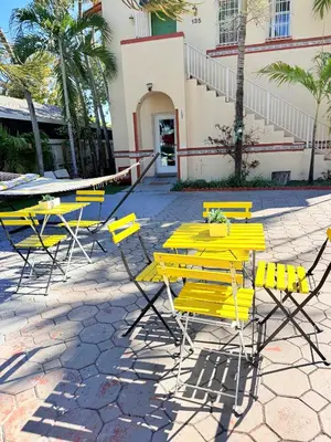 a group of yellow tables and chairs in front of a building at Beds & Sheets little Havana in Miami