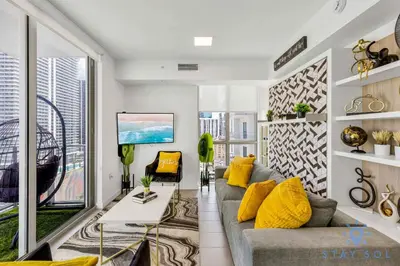 a living room with a gray couch and yellow pillows at Beautiful Apartment with gym and amazing Pool in Miami