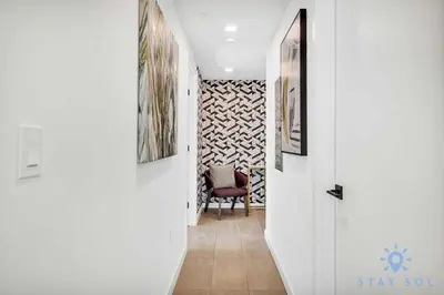 a hallway with white walls and a chair in a room at Beautiful Apartment with gym and amazing Pool in Miami