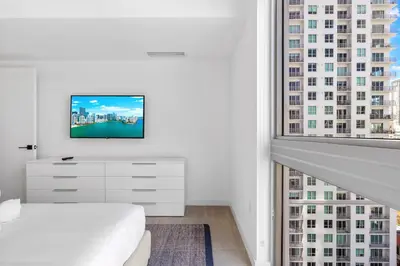 a white bedroom with a bed and a large window at Luxury One-Bedroom w Top Amenities! in Miami