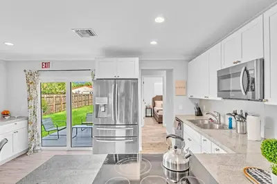 a kitchen with white cabinets and a stainless steel refrigerator at 5 Minutes to Ocean & Casino's - Large Backyard in Hollywood