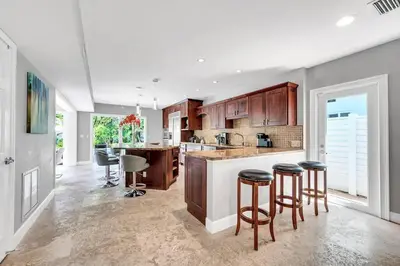 a kitchen with wooden cabinets and bar stools at Steps to Beach, Pool, Backyard Oasis, Game Room in Fort Lauderdale