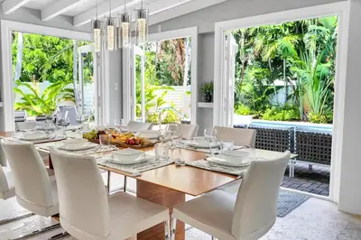 a dining room with a wooden table and white chairs at Steps to Beach, Pool, Backyard Oasis, Game Room in Fort Lauderdale
