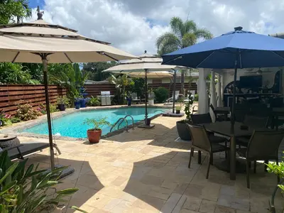 a patio with tables and umbrellas next to a pool at Wilton Manors A Mens Oasis in Fort Lauderdale