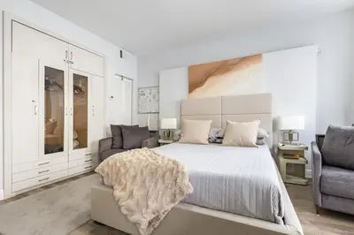 a white bedroom with a large bed and two chairs at Luxe ocean drive condo in miami south beach in Miami Beach
