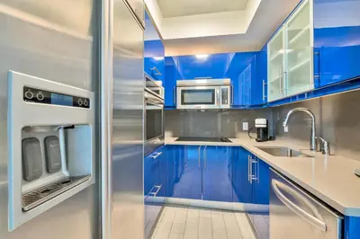 a blue kitchen with stainless steel appliances and blue cabinets at Stylish 1BR Suite with 5 Star Amenities and Stunning Views in Fort Lauderdale
