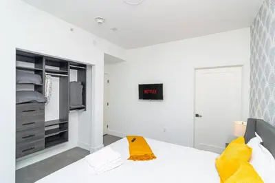 a white bedroom with a bed and a tv at Modern Cozy 2BR Oasis with King Beds Near Marlins Park & Brickell in Miami