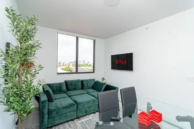 a living room with a green couch and a window at Modern Cozy 2BR Oasis with King Beds Near Marlins Park & Brickell in Miami