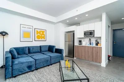 a living room with a blue couch and a kitchen at Bright 1BR with Netflix and King Bed Near Brickell and Marlins Park in Miami