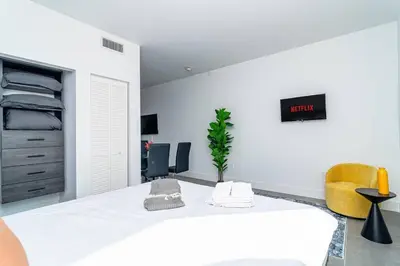 a white bedroom with a bed and two chairs at Bright 1BR with Netflix and King Bed Near Brickell and Marlins Park in Miami