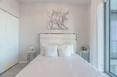 a white bed with white pillows in a bedroom at Lumiére Penthouse in Miami