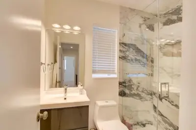 a bathroom with a sink and a toilet and a mirror at Flamingo House with Cinema, Pool & Chill Area in Miami