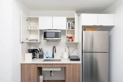 a kitchen with white cabinets and a stainless steel refrigerator at Chic Spacious Studio Miami Stay Near Marlins Park & Brickell in Miami