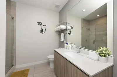 a bathroom with a sink and a toilet and a mirror at Luxury & Modern Condo in Design District with Pool in Miami