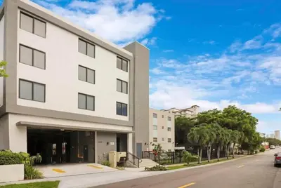 a white building on a street with a car parked in front at Cozy and Comfortable 1BR Near Calle Ocho and Brickell in Miami