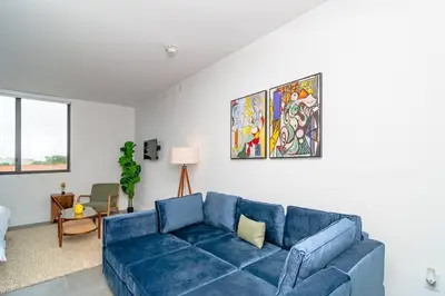 a blue couch in a living room with a painting at Cozy and Comfortable 1BR Near Calle Ocho and Brickell in Miami