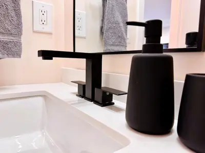 a black soap dispenser sitting on a bathroom sink at Homey Haven in Vibrant South Beach in Miami Beach