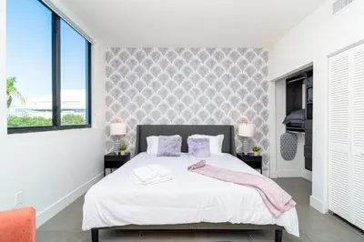 a bedroom with a bed with white sheets and purple pillows at Relaxing 1BR in Miami Close to Brickell and South Beach in Miami