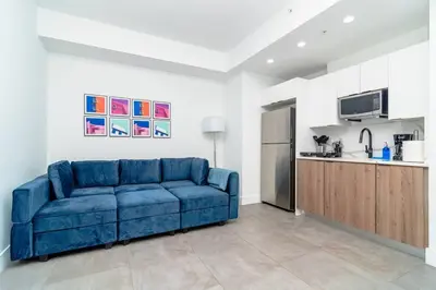 a blue couch in a living room with a kitchen at Centrally Located 1BR with King Bed Near Brickell, Airport Downtown and Wynwood in Miami