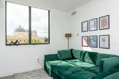a living room with a green couch and a window at Miami 2BR Getaway with King Beds Near Marlins Park & Calle Ocho in Miami