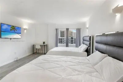 a white bedroom with two beds and a window at Skyline Paradise in Sunny Isles Beach in Sunny Isles Beach