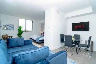 a living room with a blue couch and a bedroom at Stylish Studio Miami Suite Oasis Near Calle Ocho & Brickell in Miami