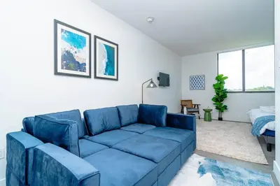 a living room with a blue couch and a bed at Stylish Studio Miami Suite Oasis Near Calle Ocho & Brickell in Miami