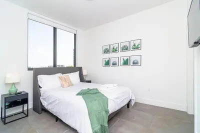 a white bedroom with a bed and a window at Stylish 2BR Miami Retreat Mins to Wynwood and Brickell in Miami
