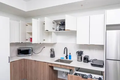a kitchen with white cabinets and a sink and a refrigerator at Stylish 2BR Miami Retreat Mins to Wynwood and Brickell in Miami