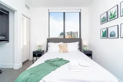 a bedroom with a white bed with a green blanket on it at Stylish 2BR Miami Retreat Mins to Wynwood and Brickell in Miami