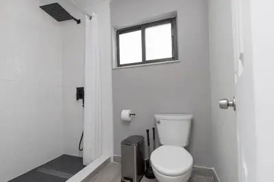 a white bathroom with a toilet and a window at Heated pool - 5min Coral Gables - Family Vacation in Miami