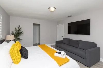 a bedroom with a bed with a couch and a flat screen tv at Heated pool - 5min Coral Gables - Family Vacation in Miami