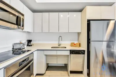 a white kitchen with a sink and a refrigerator at Amazing Apartment with Balcony & Pool in Hallandale Beach