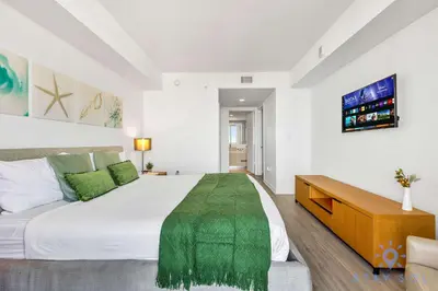 a bedroom with a large white bed and a tv at Amazing Apartment with Balcony & Pool in Hallandale Beach