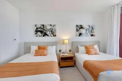 two beds in a small room with white walls at Amazing Balcony Near Beach in Hallandale Beach