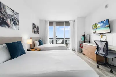 a hotel room with two beds and a desk at Deluxe Apartment with Balcony Gym & Pool in Hallandale Beach
