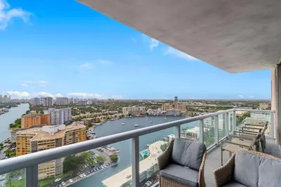 a balcony with two chairs and a river and buildings at Top Luxury Apartment with Pool & Gym in Hallandale Beach