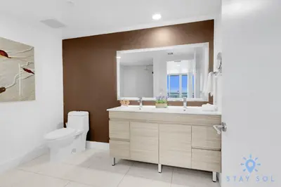 a bathroom with a sink and a toilet and a mirror at Modern 2BR 2BA Oasis & pool in Hallandale Beach