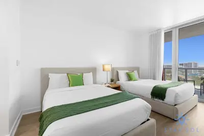 two beds in a room with a window at Modern 2BR 2BA Oasis & pool in Hallandale Beach