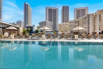 a swimming pool with chairs and umbrellas in a city at Modern 2BR 2BA Oasis & pool in Hallandale Beach