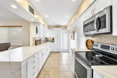 a large kitchen with white cabinets and appliances at Coral Shores Waterfront Heated Pool Hosts 14! in Fort Lauderdale