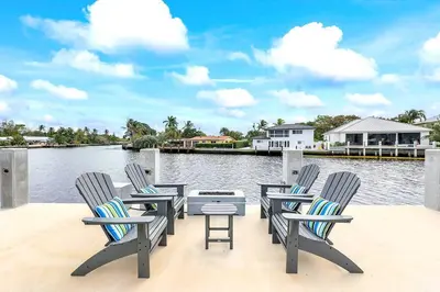 a group of chairs sitting on a deck next to the water at Coral Shores Waterfront Heated Pool Hosts 14! in Fort Lauderdale